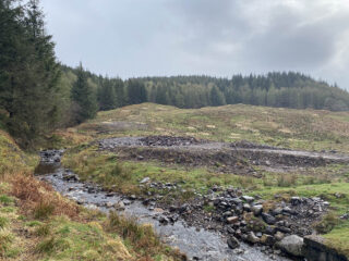 Stream in the foregrpund of a rocky boggy field